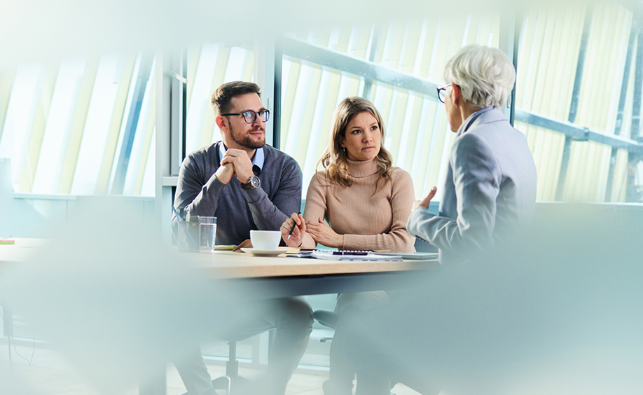 Three people meeting in open space around a conference table