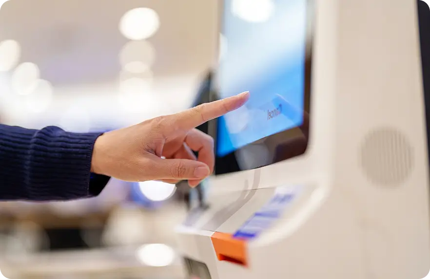 Person using a touchscreen kiosk by tapping options on the display