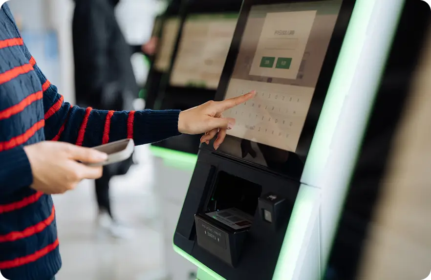 Person using a touchscreen kiosk by tapping options on the display