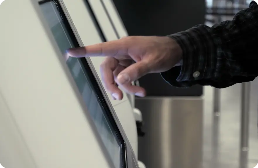 Person using a touchscreen kiosk by tapping options on the display