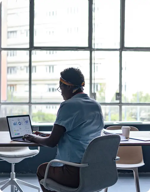 Person seated in an office setting with an open laptop displaying an analytics dashboard.