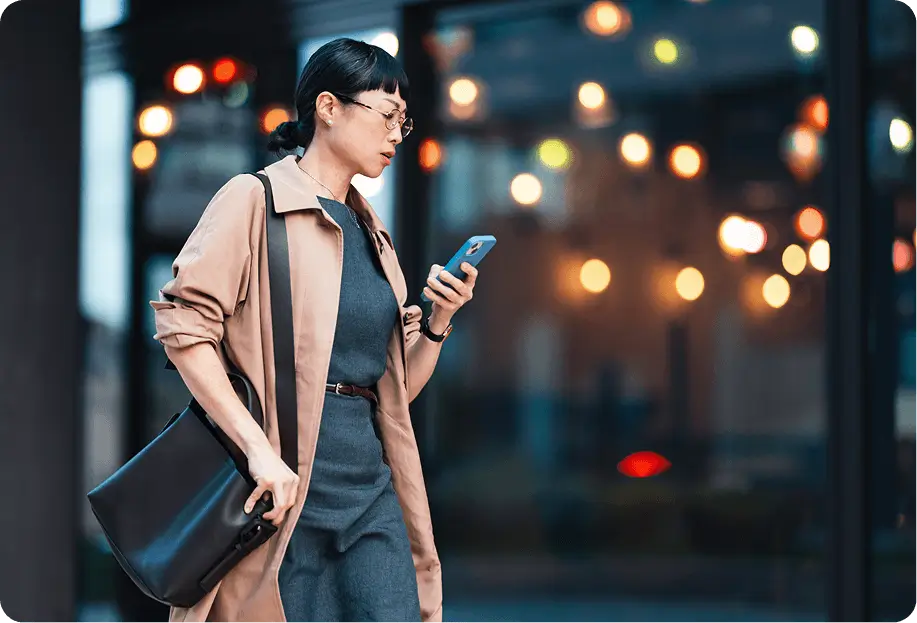 Person walking outside, looking down at their phone.